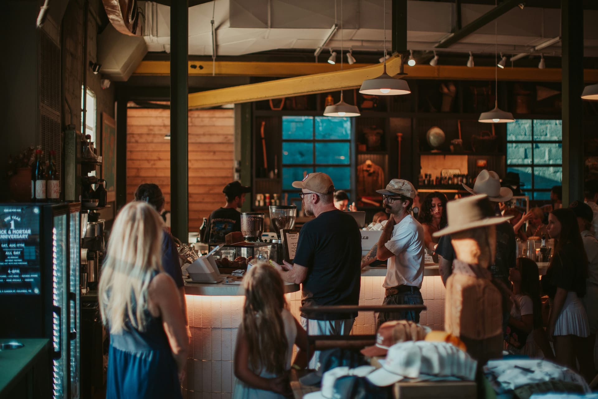 Busy warm-lit retail cafe counter with customers browsing